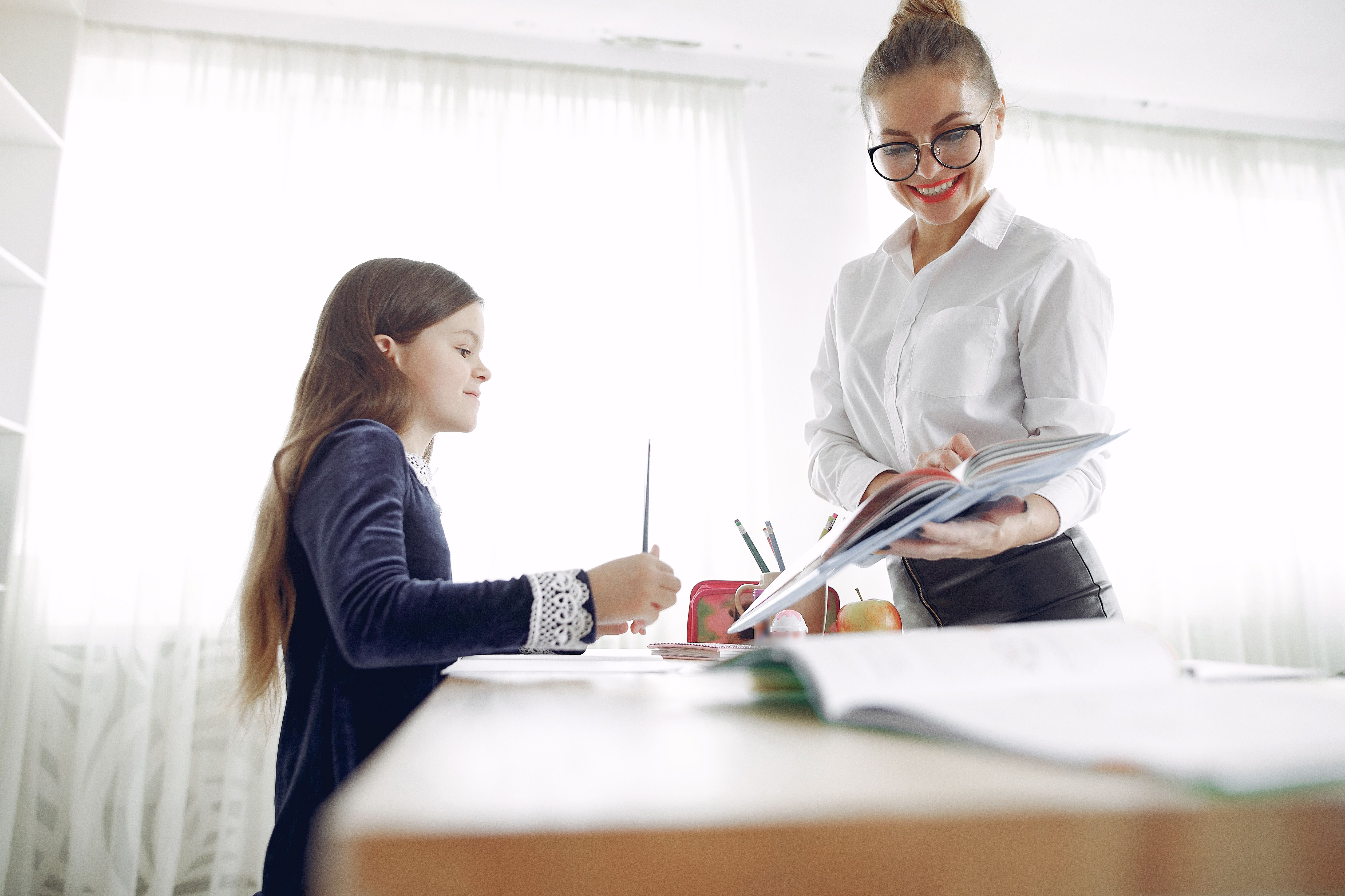 Girl receiving one-to-one teaching support from a female teacher at a classroom desk